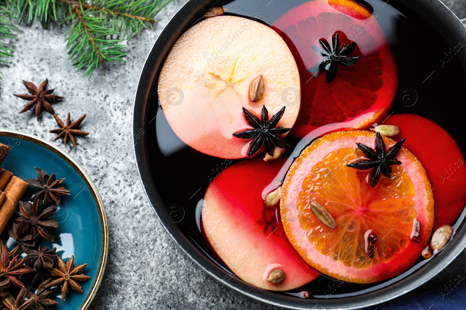 Photo of Delicious mulled wine and ingredients on grey table, flat lay