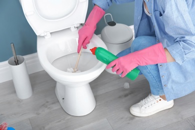 Photo of Woman cleaning toilet bowl in bathroom