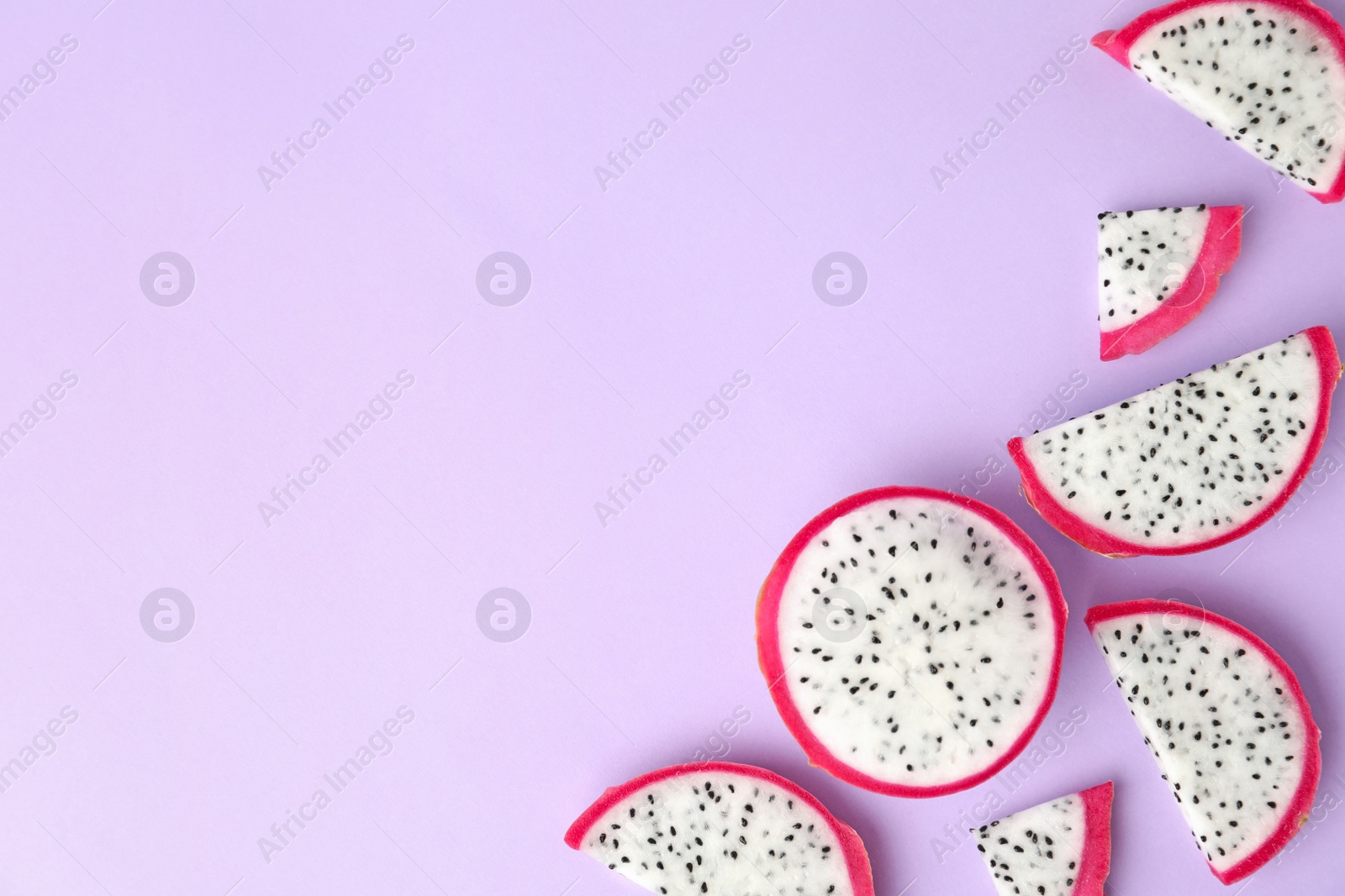 Photo of Slices of delicious dragon fruit (pitahaya) on violet background, flat lay. Space for text