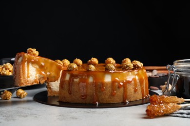 Photo of Taking piece of delicious caramel cheesecake with popcorn on light grey table