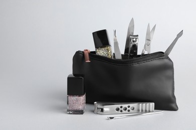 Set of manicure tools in bag on grey background