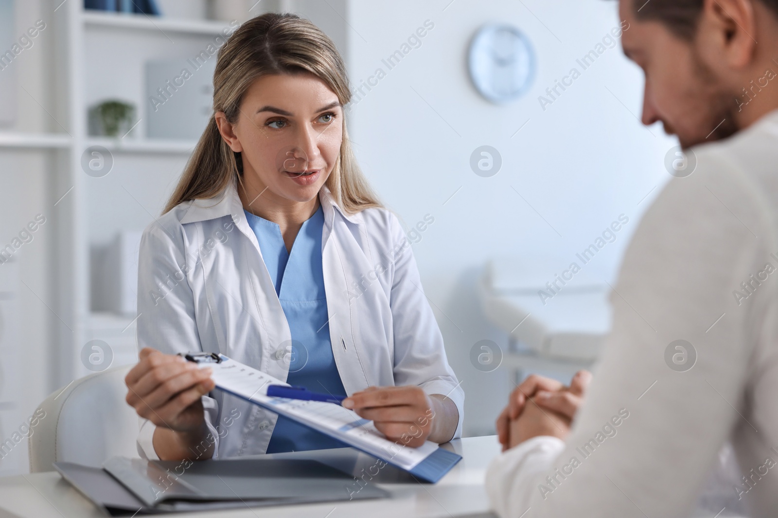 Photo of Professional doctor working with patient at white table in hospital