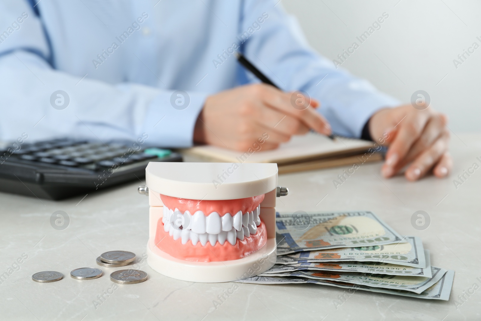 Photo of Educational dental typodont model and money on light grey table. Expensive treatment