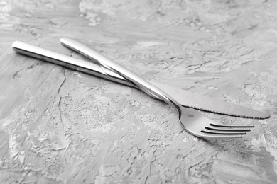 Photo of Stylish cutlery. Silver knife and fork on grey textured table