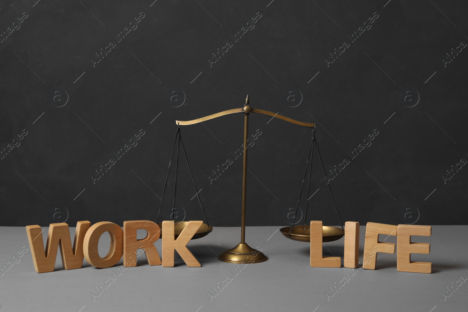 Photo of Words Life and Work made of wooden letters near scales on grey table. Balance concept