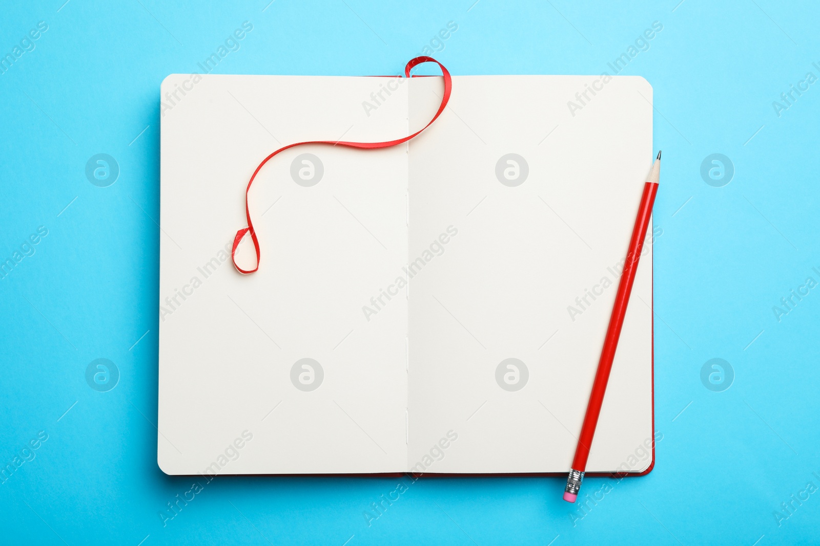 Photo of Stylish open notebook and pencil on light blue background, top view