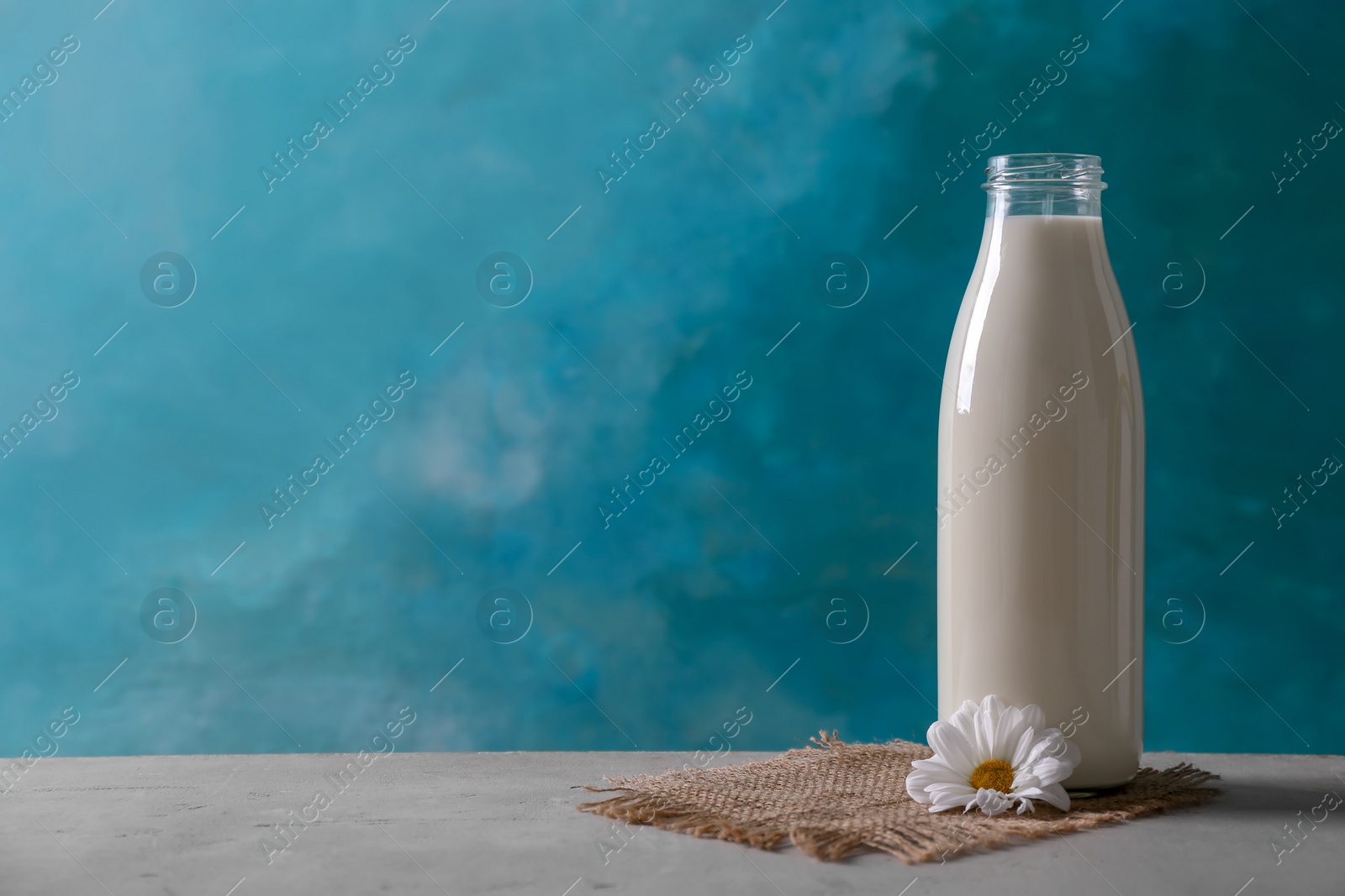 Photo of Bottle of fresh milk on table against color background