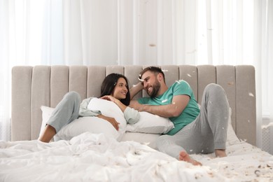 Photo of Happy young couple resting after fun pillow fight in bedroom