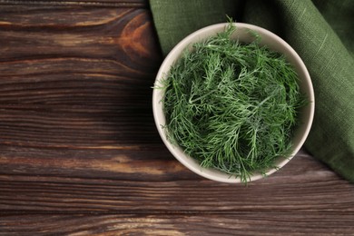 Photo of Bowl of fresh dill on wooden table, top view. Space for text