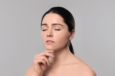 Photo of Young woman massaging her face on grey background