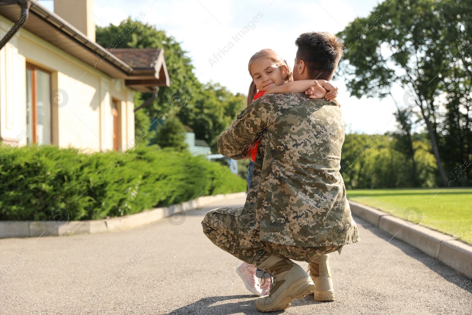 Photo of Father in military uniform hugging little daughter outdoors