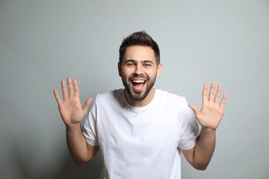 Photo of Young man laughing on light grey background. Funny joke