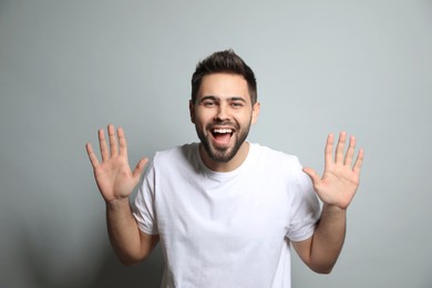 Young man laughing on light grey background. Funny joke