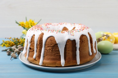 Photo of Glazed Easter cake with sprinkles on light blue wooden table