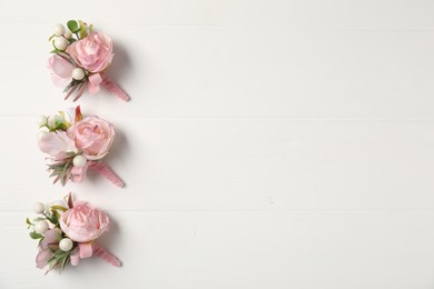 Photo of Beautiful boutonnieres on white background, flat lay. Space for text