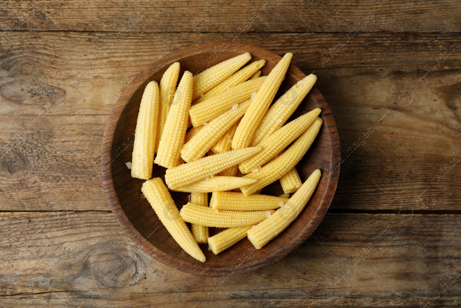 Photo of Fresh baby corn cobs on wooden table, top view