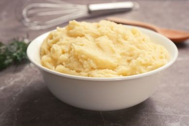 Photo of Bowl with mashed potatoes on grey table