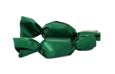 Photo of Delicious candies in dark green wrappers on white background