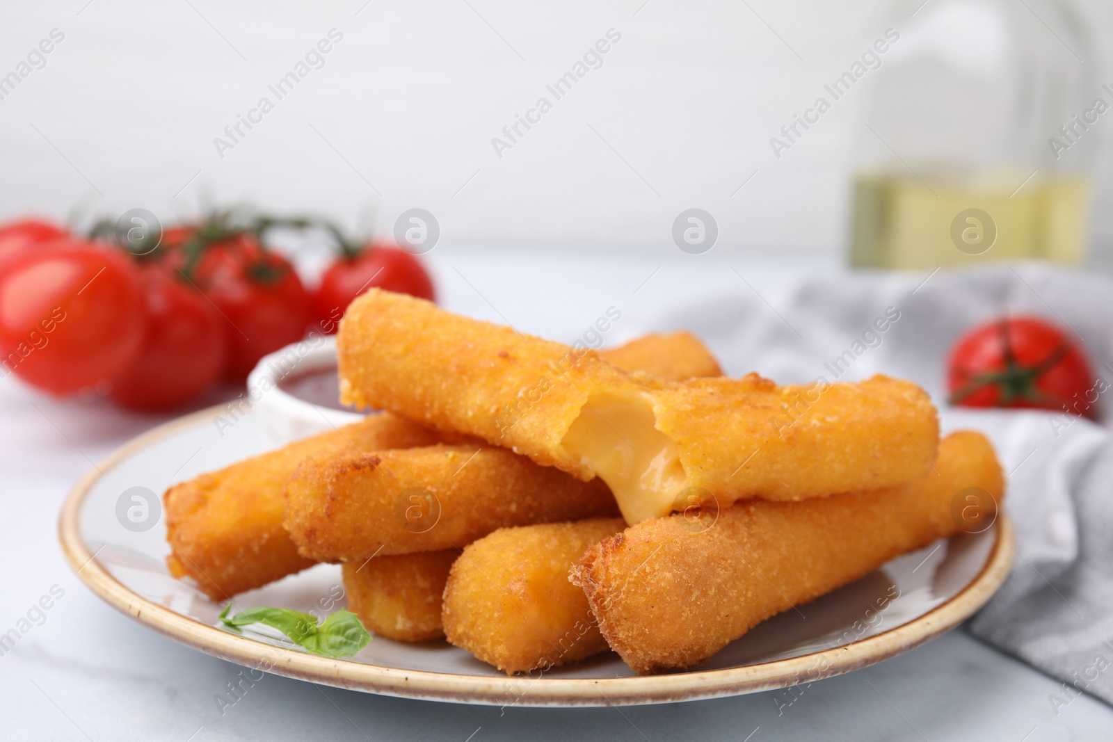 Photo of Tasty fried mozzarella sticks on white marble table