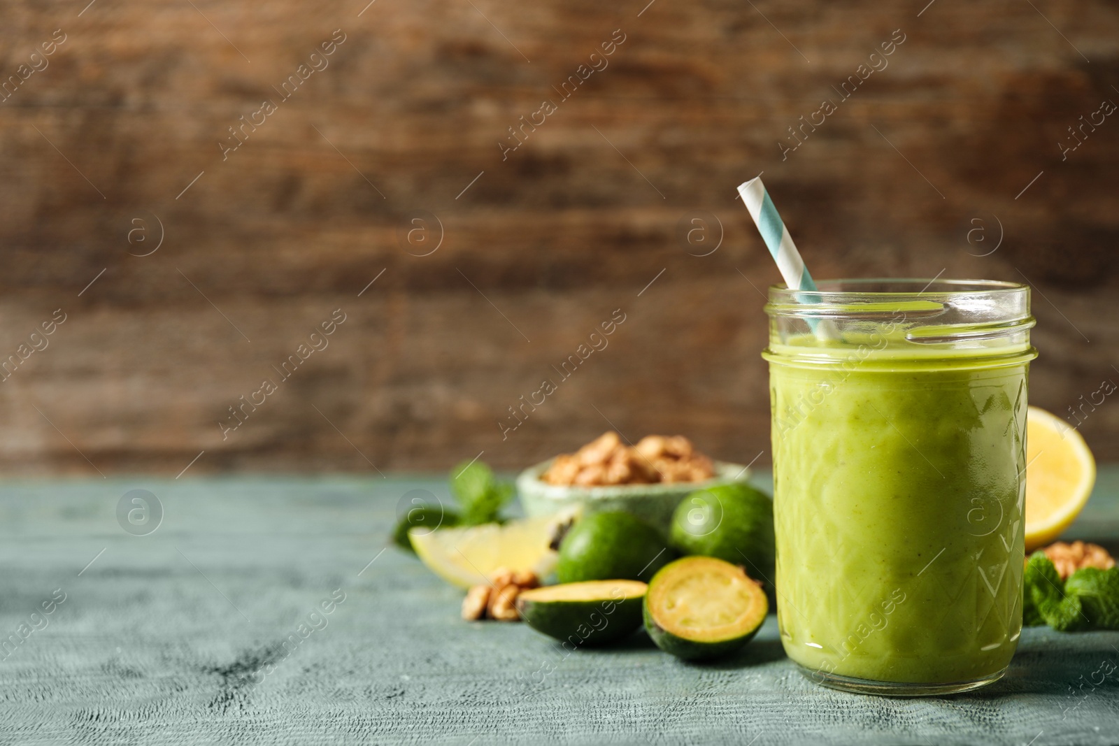 Photo of Fresh feijoa smoothie and fresh fruits on wooden table. Space for text