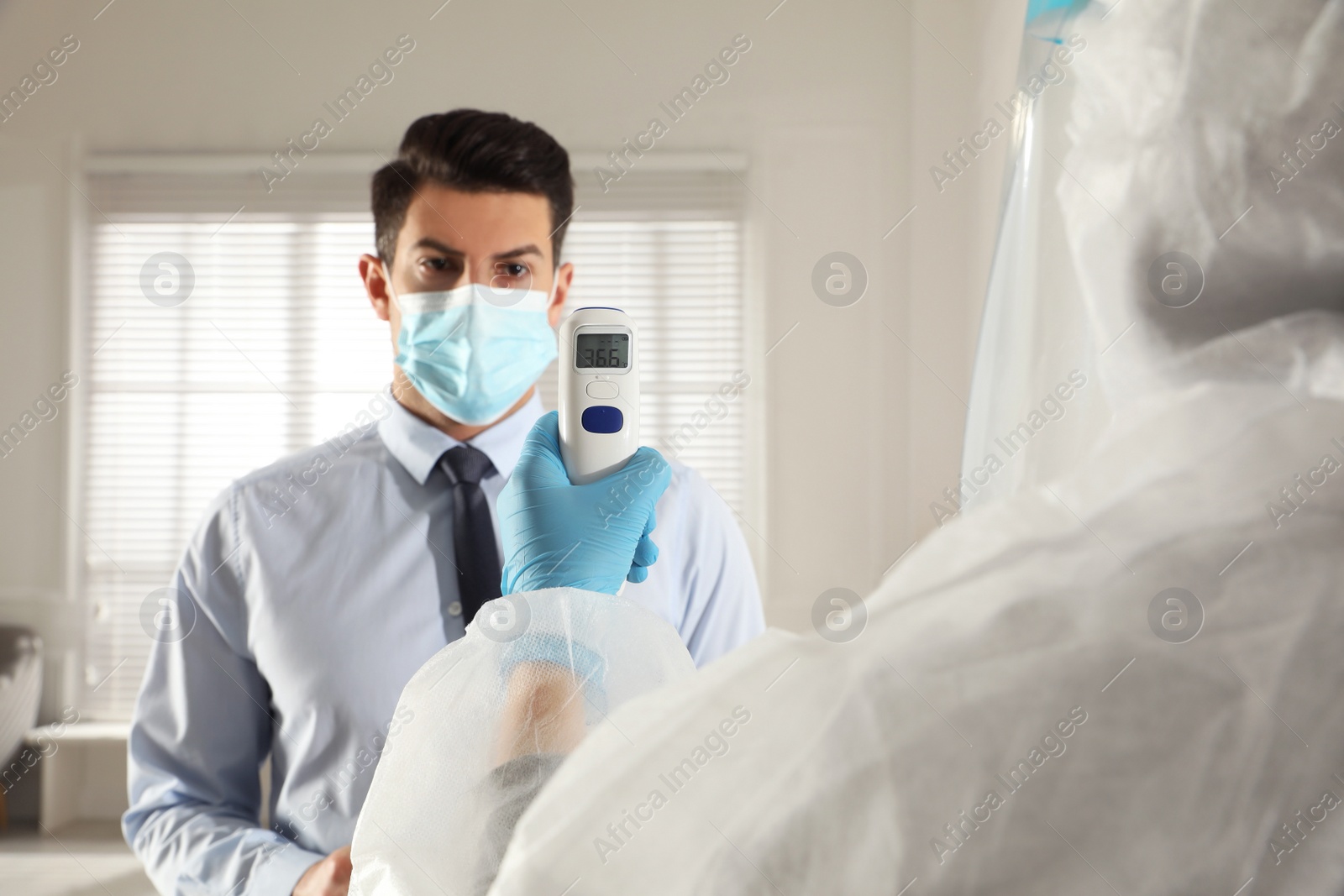 Photo of Doctor measuring man's temperature in office closeup. Prevent spreading of Covid-19