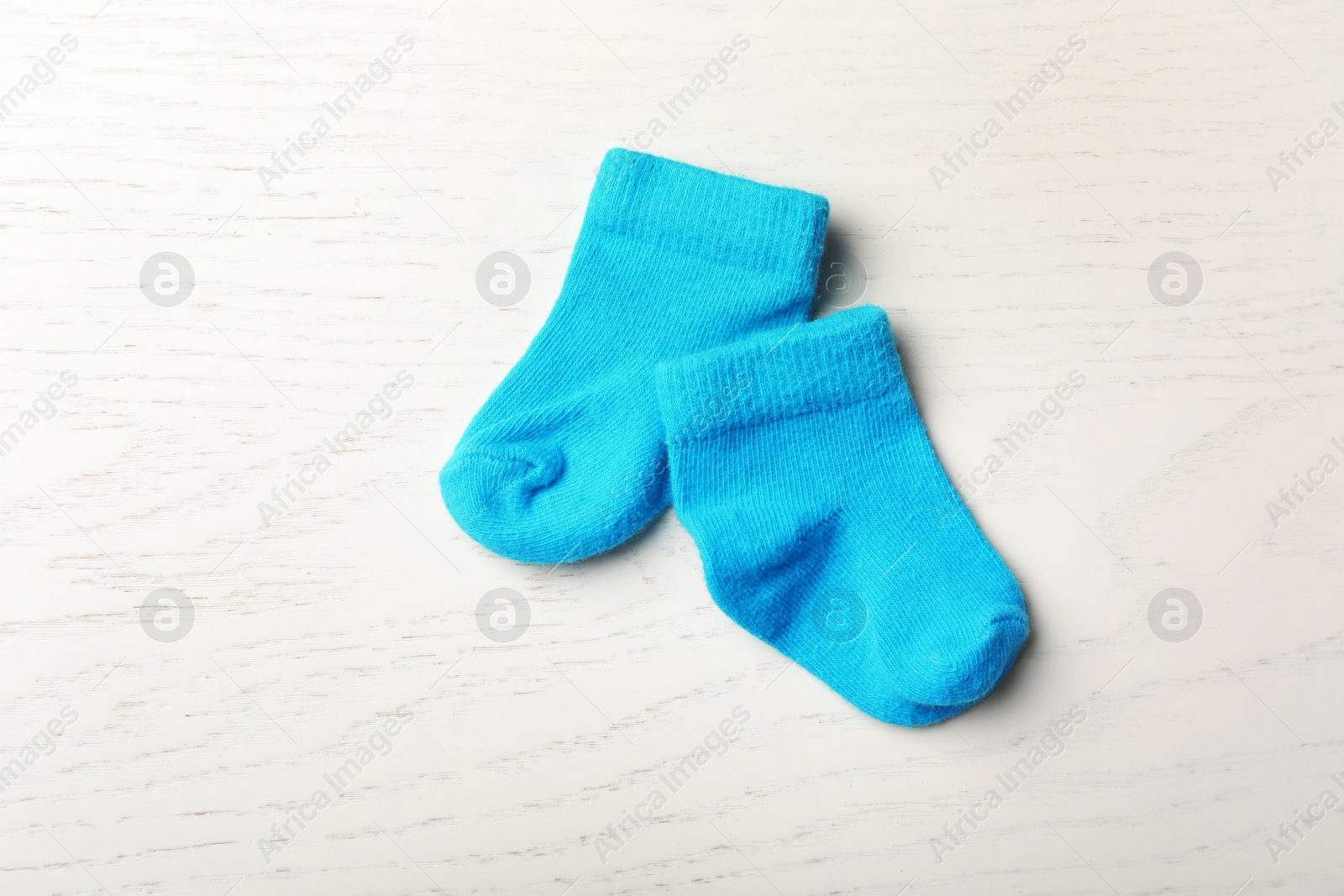Photo of Pair of cute child socks on white wooden background, top view