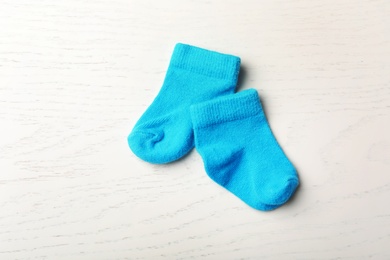 Photo of Pair of cute child socks on white wooden background, top view