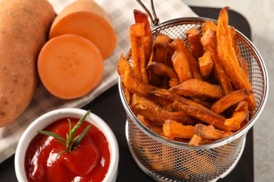 Photo of Sweet potato fries and ketchup on board, closeup