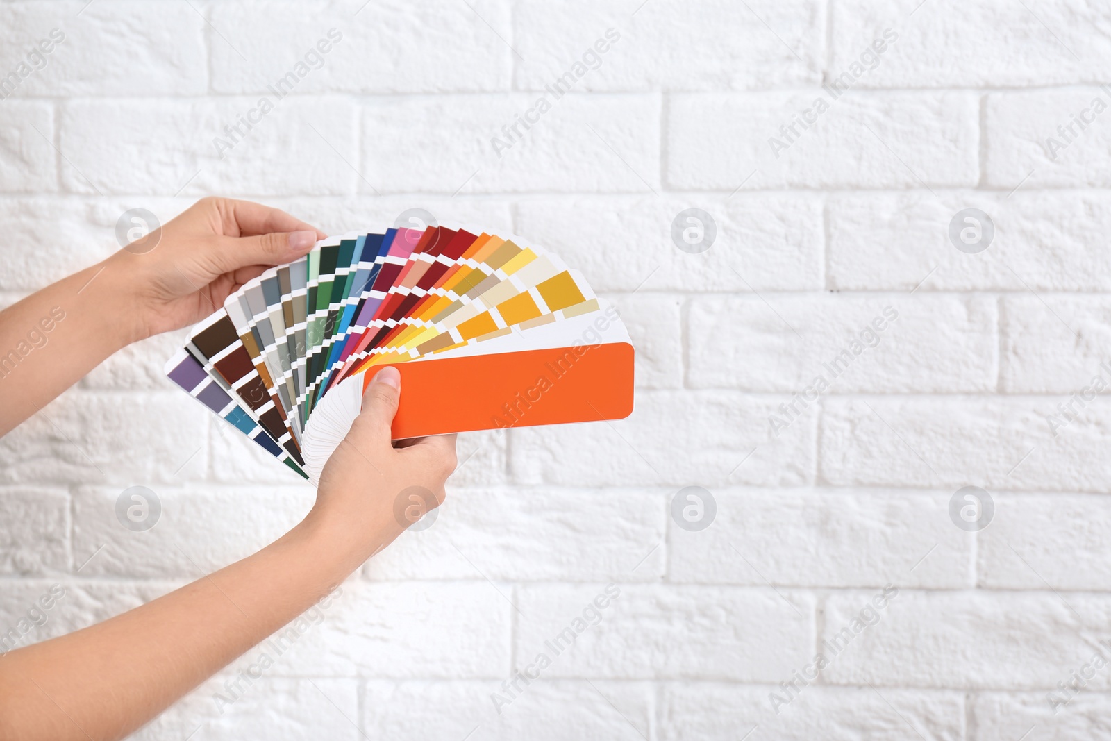 Photo of Female interior designer with color palette samples near brick wall, closeup. Space for text