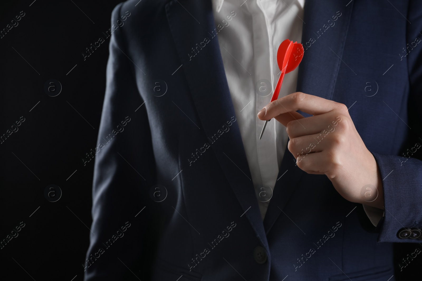 Photo of Businesswoman holding red dart on black background, closeup