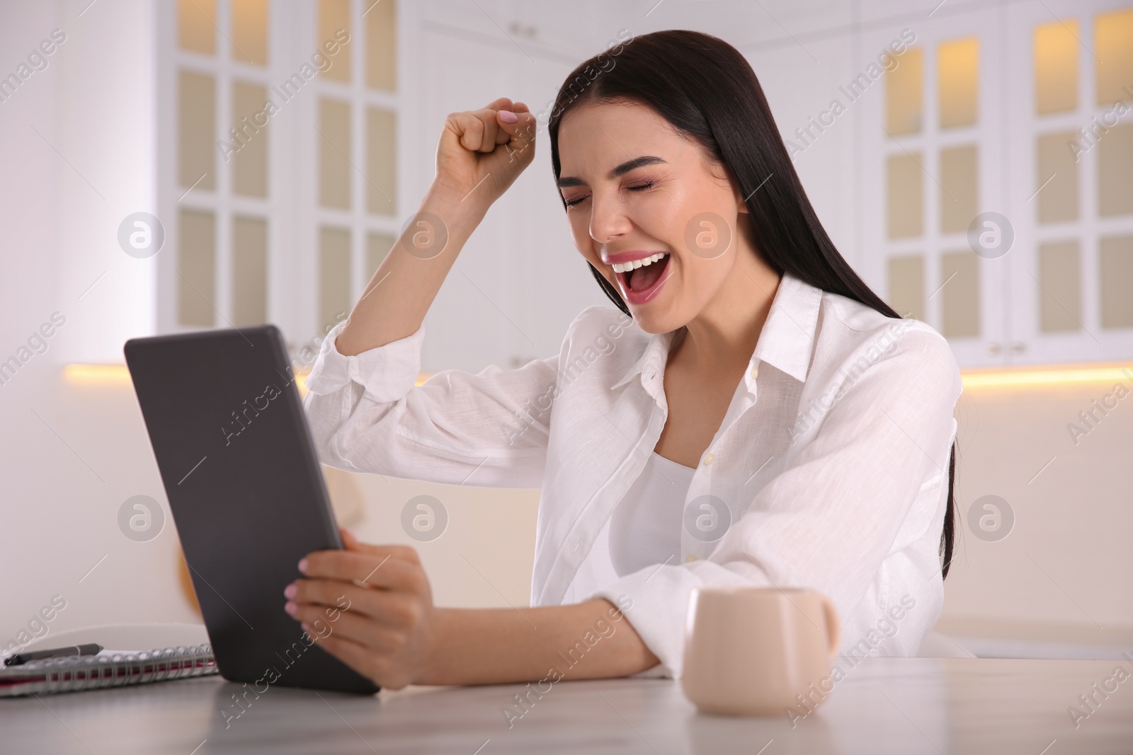 Photo of Emotional woman participating in online auction using tablet at home