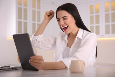 Photo of Emotional woman participating in online auction using tablet at home