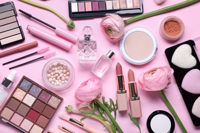 Flat lay composition with different makeup products and beautiful spring flowers on pink background