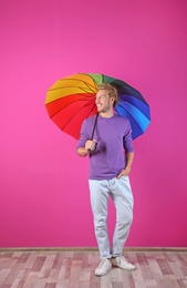 Man with rainbow umbrella near color wall