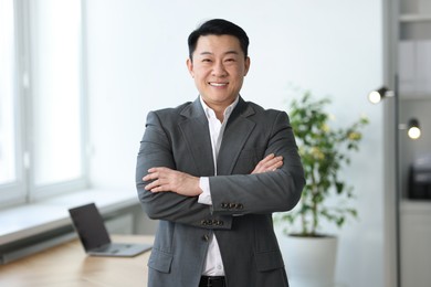 Photo of Portrait of smiling businessman with crossed arms in office