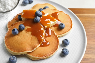 Delicious pancakes with fresh blueberries, butter and syrup on wooden table, closeup