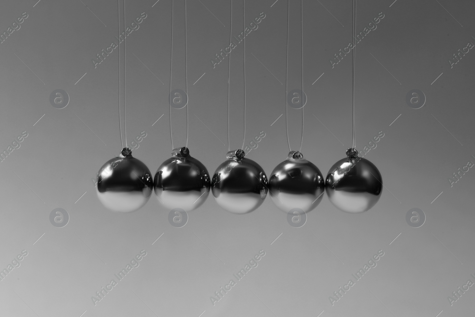 Photo of Newton's cradle on grey background. Physics law of energy conservation