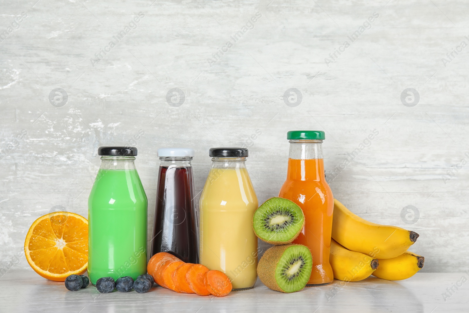 Photo of Bottles with different drinks and ingredients on table against color background