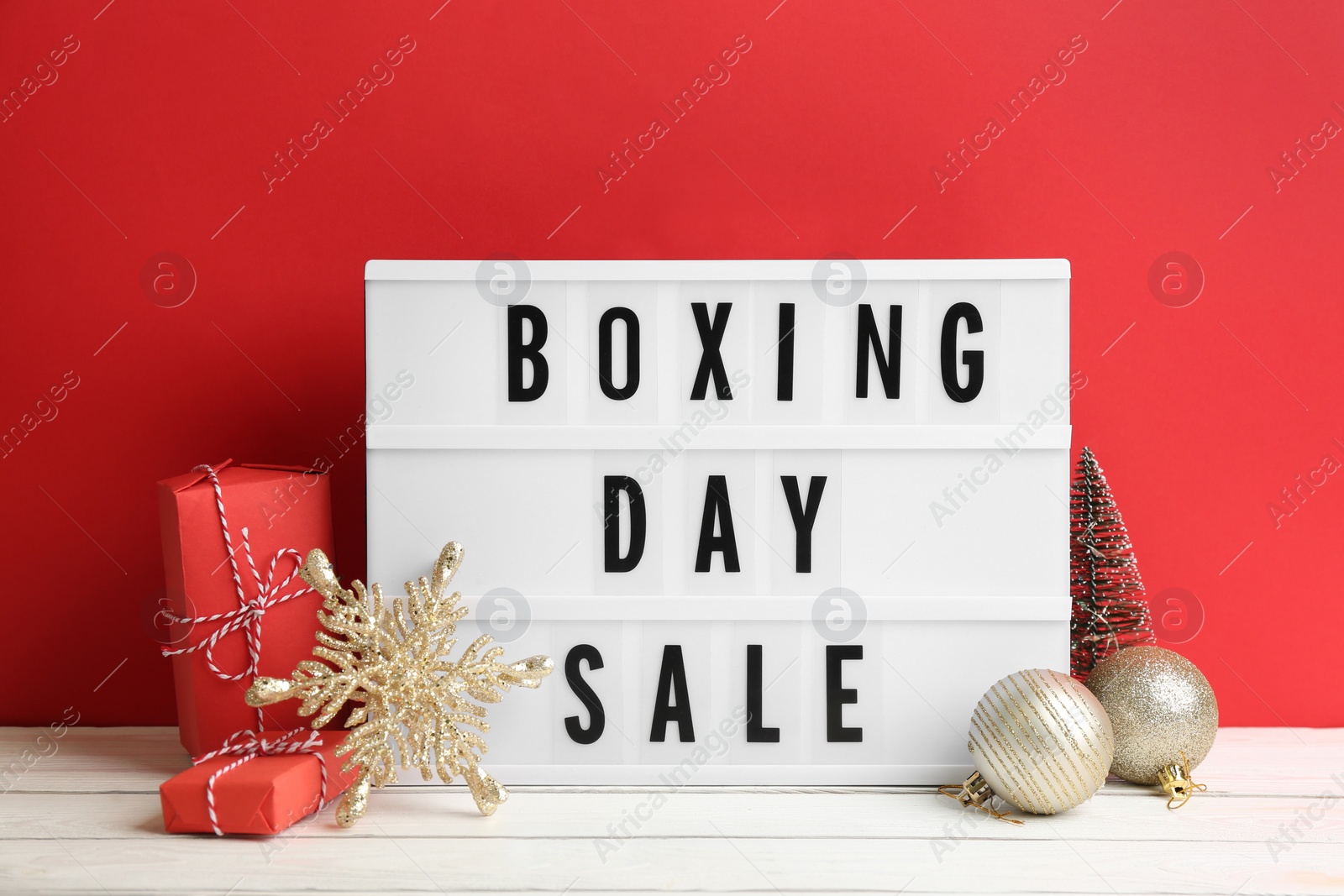 Photo of Composition with Boxing Day Sale sign and Christmas gifts on white table against red background