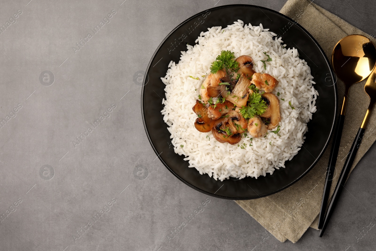 Photo of Delicious rice with parsley and mushrooms served on grey table, flat lay. Space for text
