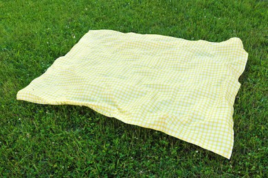 Photo of Checkered picnic tablecloth on fresh green grass outdoors