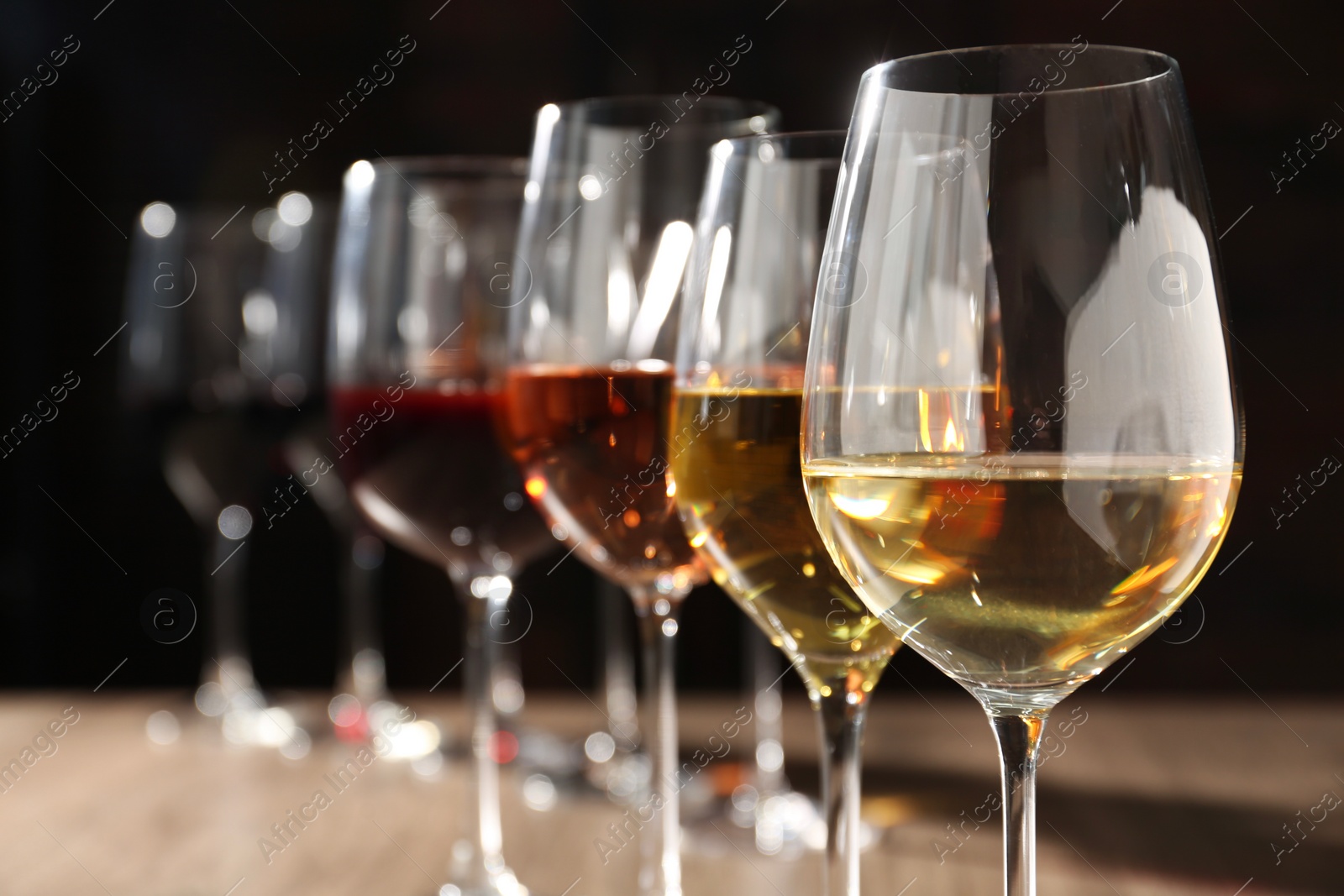 Photo of Different tasty wines in glasses against blurred background, closeup