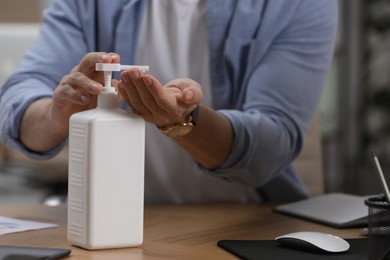 Photo of Man applying hand sanitizer in office, closeup. Personal hygiene during Coronavirus pandemic