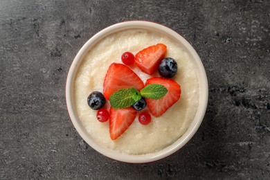 Photo of Delicious semolina pudding with berries and mint on grey table, top view