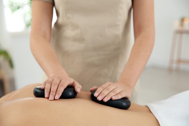 Photo of Man receiving hot stone massage in spa salon, closeup