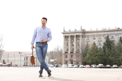 Handsome young man in stylish outfit and leather shoes outdoors