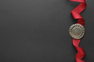 Gold medal on black background, top view with space for text. Symbol of victory