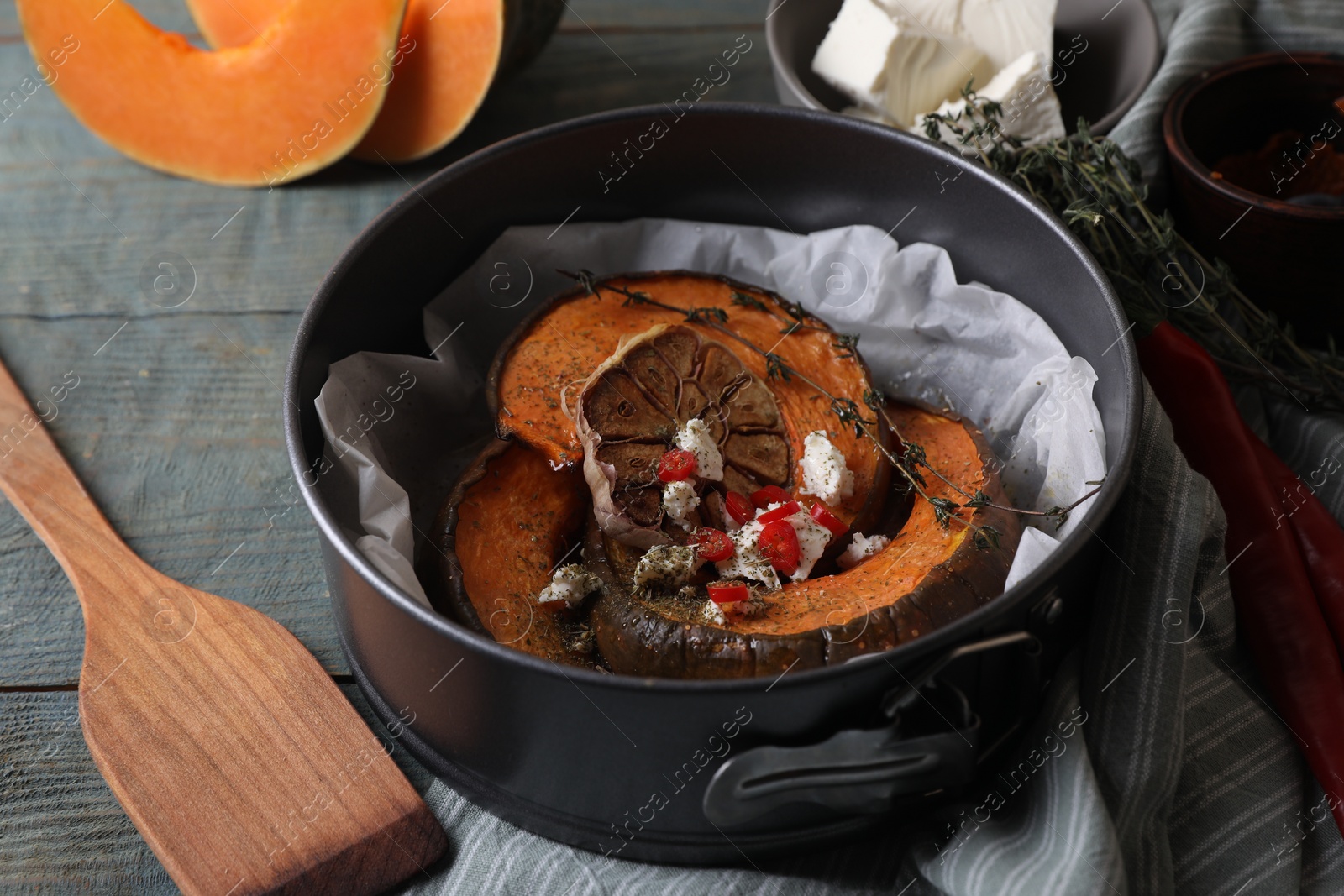 Photo of Freshly baked pumpkin slices with cheese, garlic, chili pepper and thyme on grey wooden table