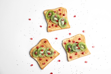 Photo of Tasty toasts with kiwi, peanut butter, pomegranate and chia seeds on white background, top view