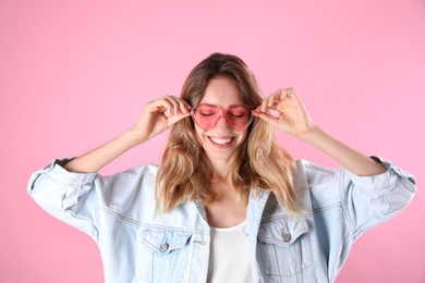 Photo of Young beautiful woman wearing heart shaped glasses on pink background